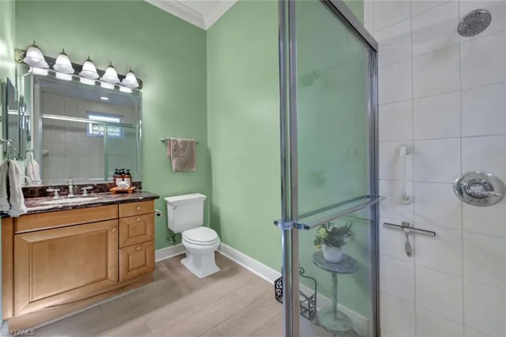 En-suite full bath with a shower stall, vanity, and crown molding