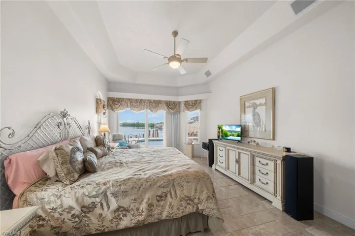Bedroom with a tray ceiling, access to outside, and ceiling fan