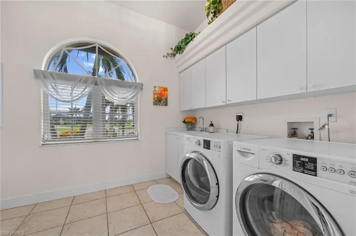 Laundry area featuring light tile patterned floors, cabinet space, and separate washer and dryer
