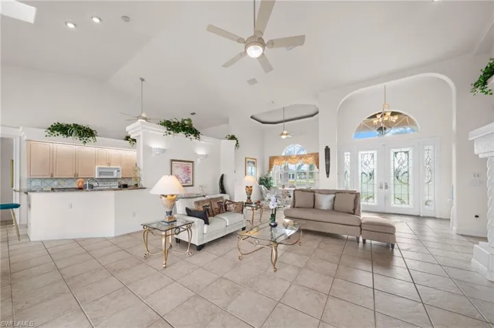 Living room featuring high vaulted ceiling, ceiling fan, a chandelier, french doors, and light tile patterned flooring