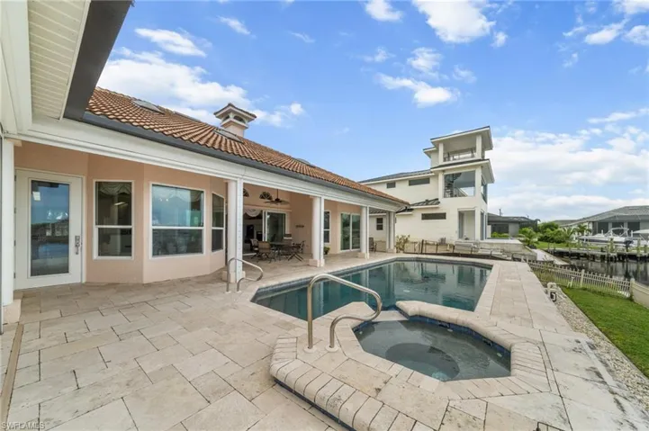 Rear view of property featuring a patio, a tiled roof, stucco siding, and a pool with connected hot tub