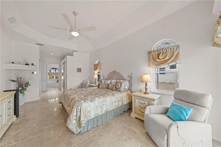Bedroom with a raised ceiling, a closet, a ceiling fan, and ensuite bath