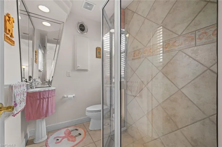 Full bathroom featuring light tile patterned floors and a shower stall