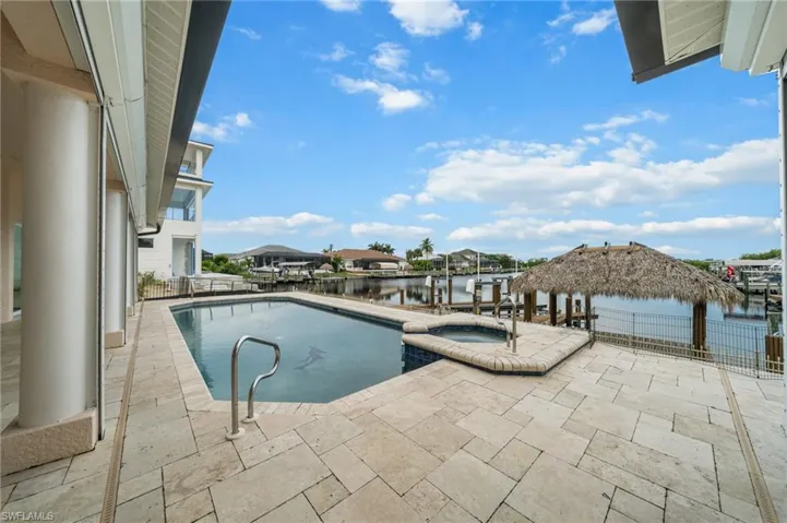 View of swimming pool with a pool with connected hot tub, a patio area, and a water view