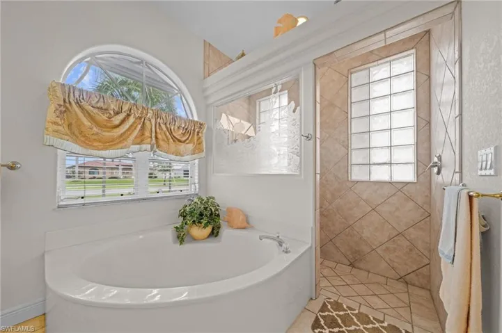 Bathroom featuring a bath, light tile patterned floors, and a shower stall