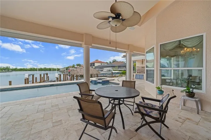 View of patio / terrace with ceiling fan, a water view, a pool with connected hot tub, and a dock