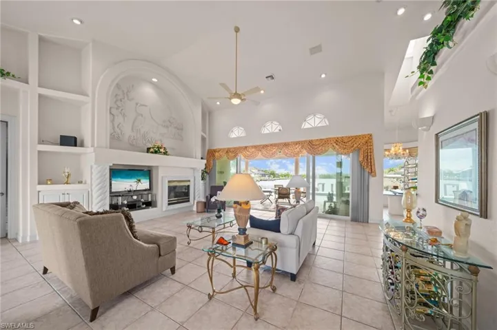 Living area featuring built in features, a ceiling fan, light tile patterned flooring, recessed lighting, and a glass covered fireplace
