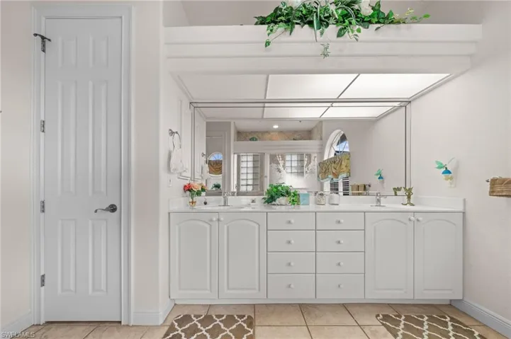 Full bathroom with double vanity, light tile patterned floors, and a shower stall