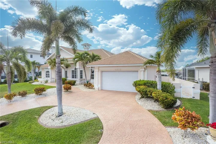 Mediterranean / spanish-style house with a front yard, decorative driveway, an attached garage, and stucco siding