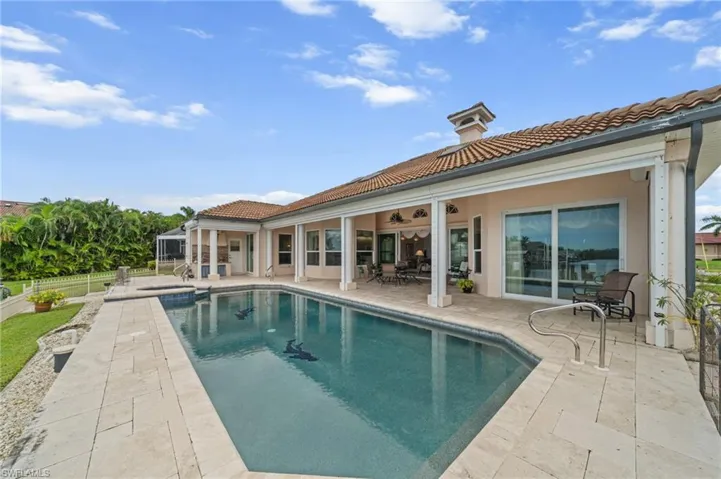 Back of house with a patio area, a tiled roof, a pool with connected hot tub, and stucco siding
