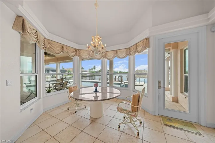 Tiled dining area featuring a chandelier and a water view