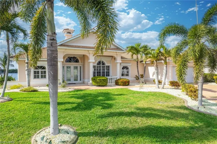 Rear view of property featuring a lawn, french doors, stucco siding, and a porch