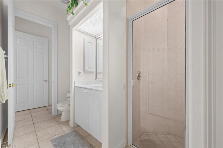 Full bath with a stall shower, vanity, and light tile patterned floors