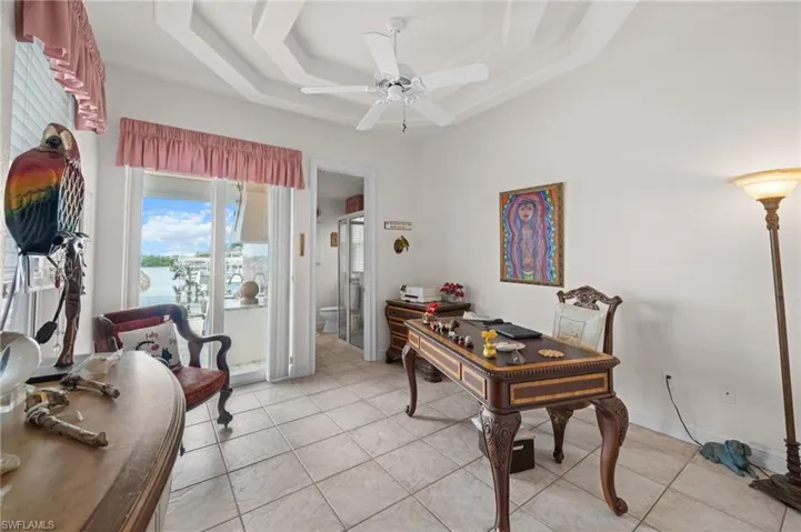 Office featuring light tile patterned floors, a raised ceiling, and ceiling fan