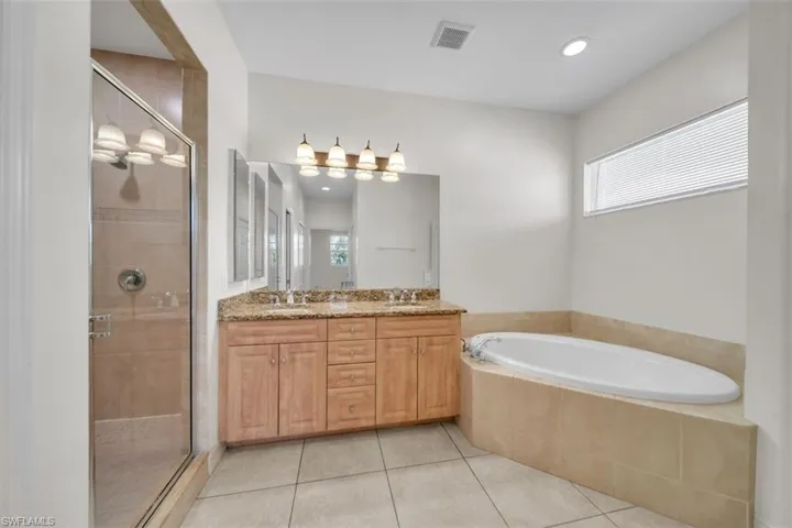 Bathroom with a garden tub, a shower stall, double vanity, light tile patterned flooring, and recessed lighting