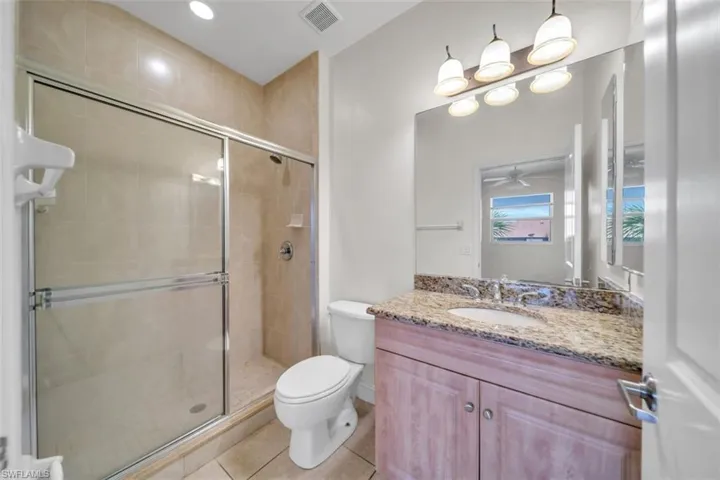 Bathroom with a shower stall, light tile patterned floors, vanity, recessed lighting, and ceiling fan