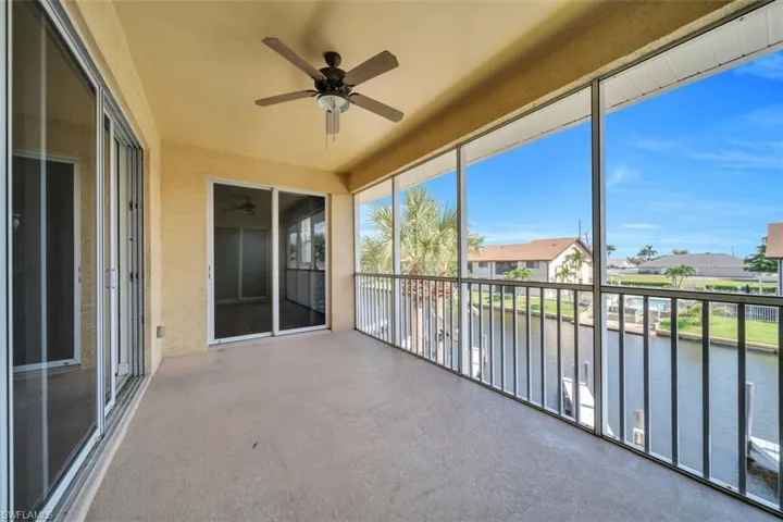 Unfurnished sunroom with a water view, a ceiling fan, and a balcony
