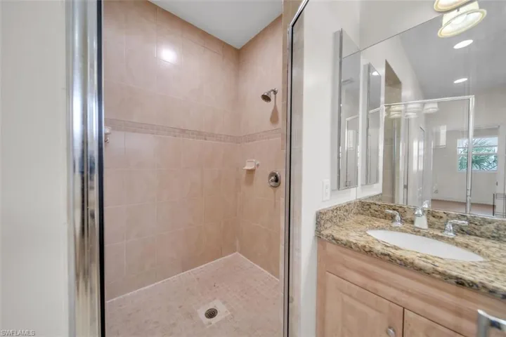 Bathroom with a stall shower, vanity, and recessed lighting