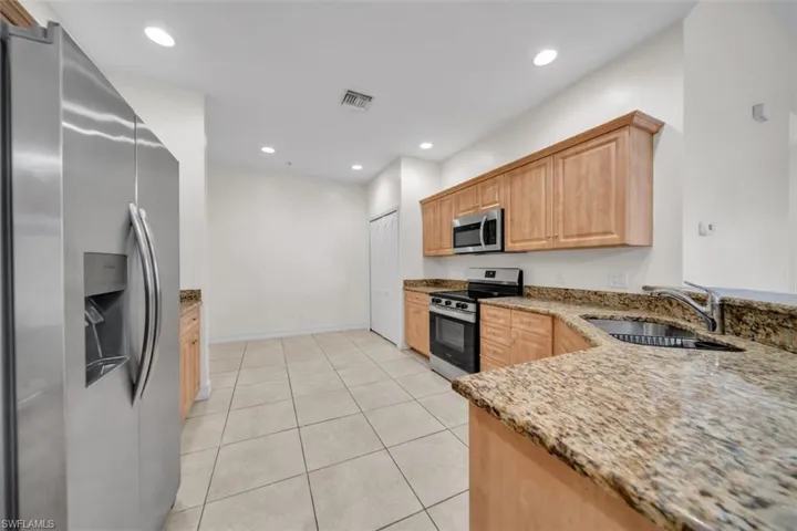 Kitchen featuring stainless steel appliances, light brown cabinets, light stone countertops, light tile patterned floors, and recessed lighting