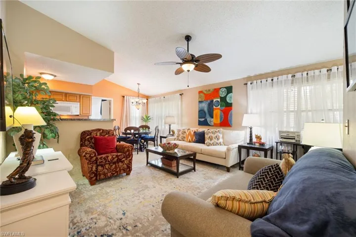 Open-concept living area featuring vaulted ceilings, a ceiling fan, and light wall tones