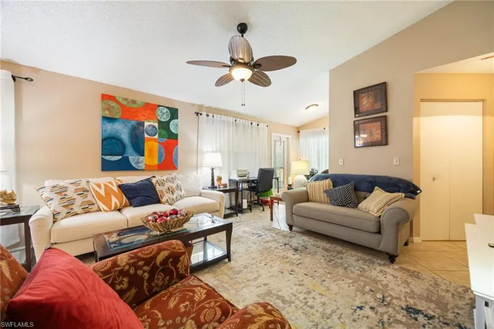 Open-concept living area featuring a ceiling fan, vaulted ceiling, and neutral wall tones