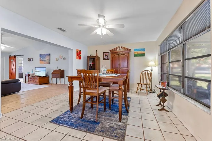 Dining area featuring light tile floors, ceiling fan, and view of the living room