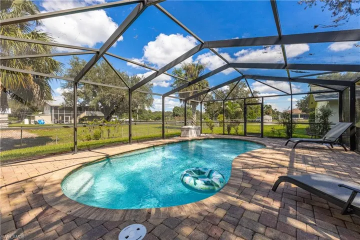 Screened pool enclosure featuring a custom-shaped swimming pool, paver deck, and metal framing