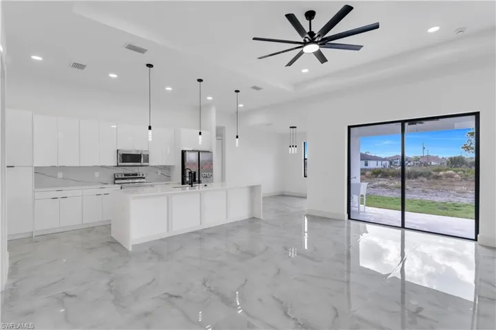 Kitchen with white cabinetry, modern cabinets, decorative light fixtures, a center island with sink, and stainless steel appliances
