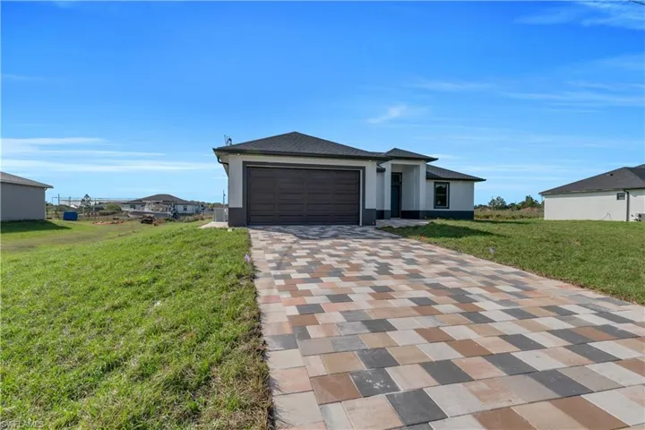 View of front of property with a front lawn, driveway, a garage, stucco siding, and roof with shingles