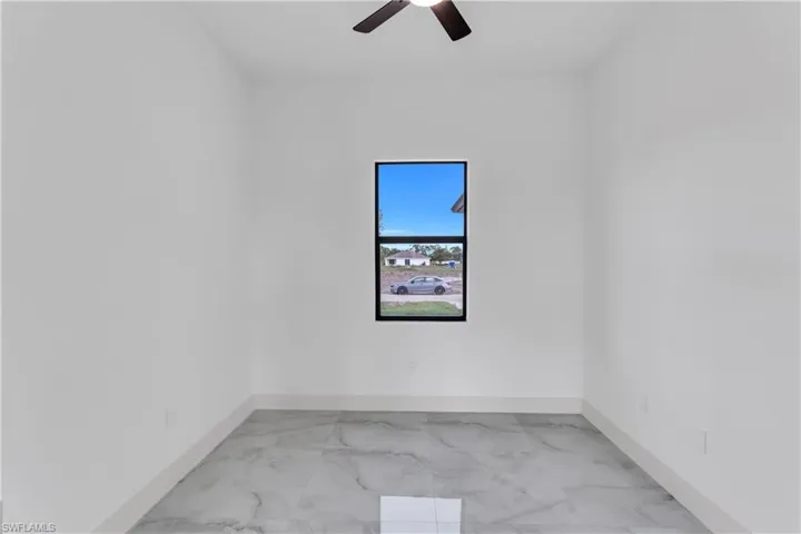Spare room with light marble finish flooring and a ceiling fan