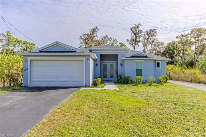Ranch-style home featuring stucco siding, driveway, french doors, and a garage