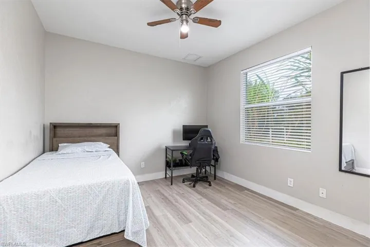Bedroom with light wood-style floors, a ceiling fan, and a desk