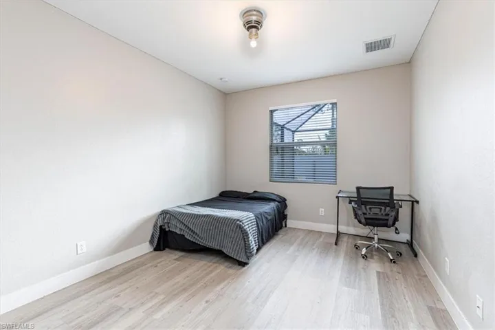 Bedroom with light wood finished floors and a desk