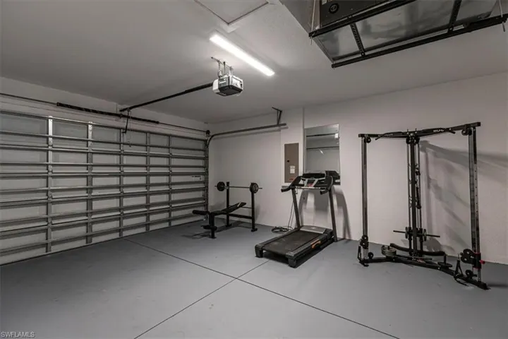 Workout area with a garage, finished concrete floors, and electric panel