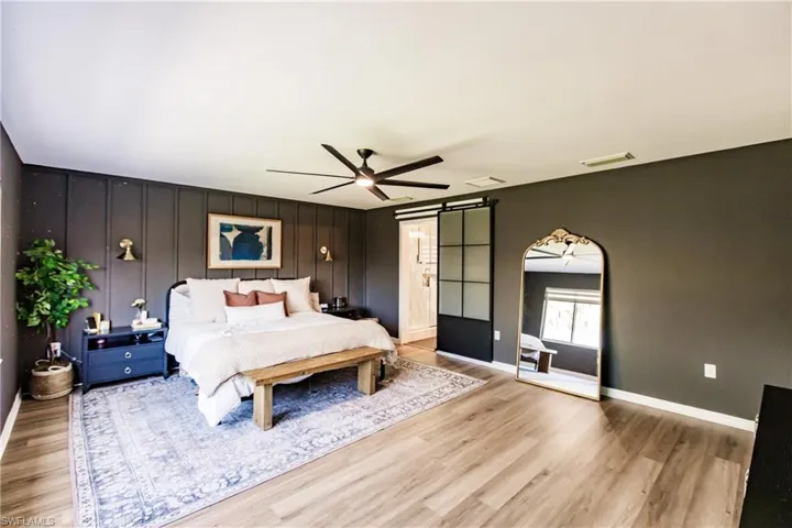Bedroom featuring a barn door, ceiling fan, and hardwood / wood-style floors