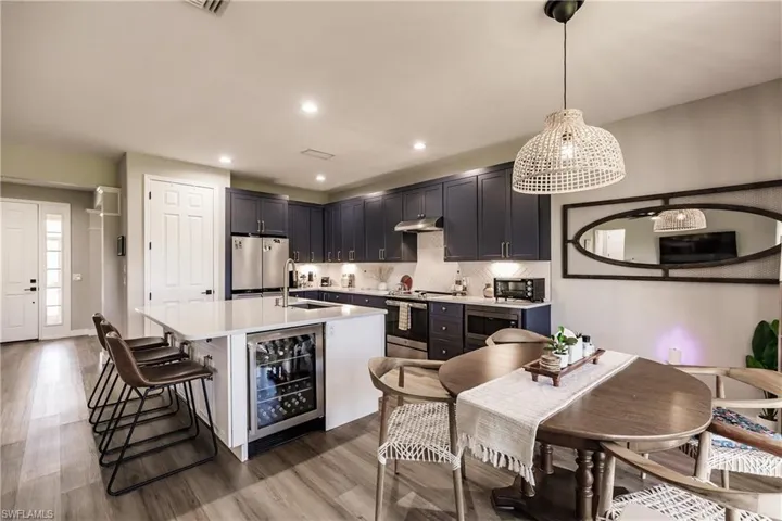 Kitchen featuring stainless steel appliances, a kitchen island with sink, wood-type flooring, wine cooler, and sink