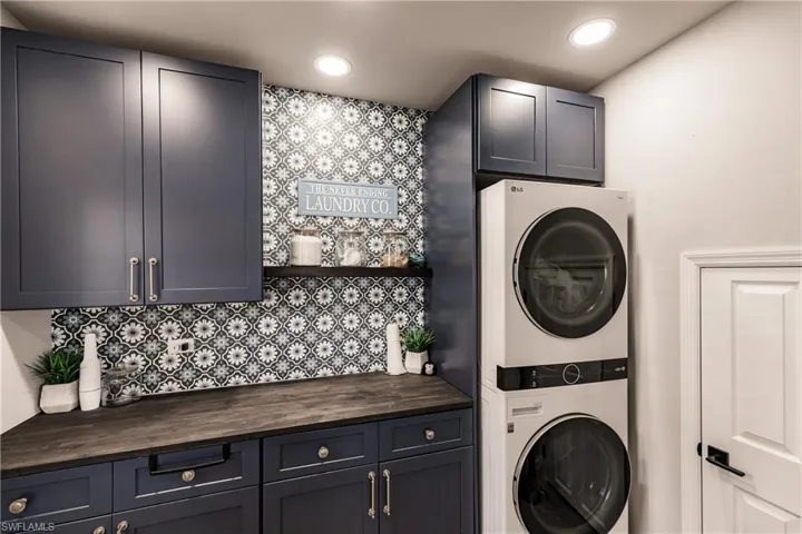 Laundry area with stacked washer and clothes dryer and cabinets