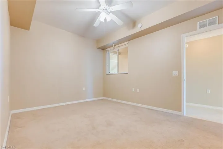 Unfurnished primary room featuring a window, light carpet and ceiling fan.