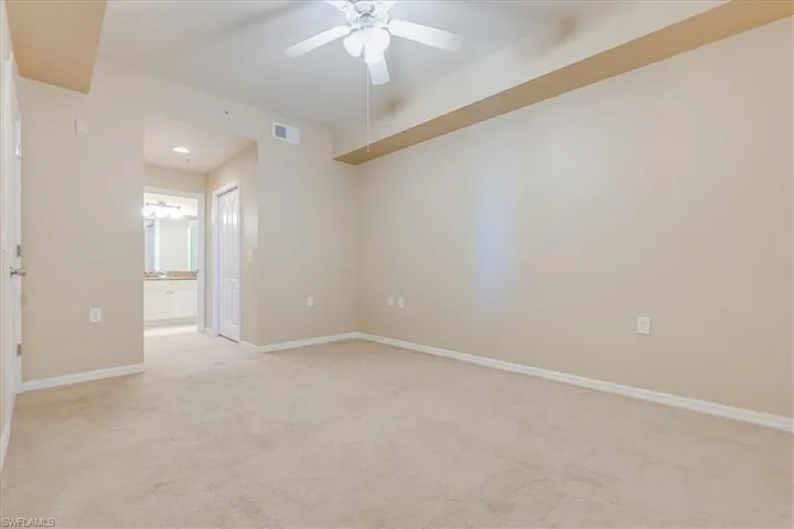 Capacious primary bedroom with plush carpet, a closet and view of primary bathroom.