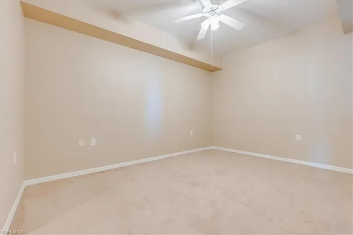 Unfurnished room with light colored carpet and ceiling fan.