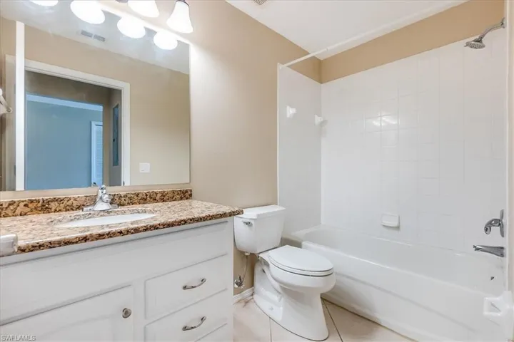 Full bathroom featuring tile patterned flooring, vanity, toilet, and tiled shower / bath combo.