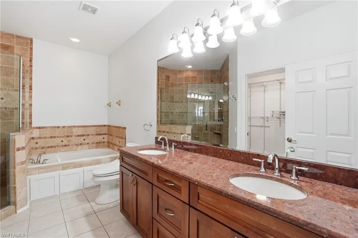 Full bath featuring a spacious closet, a shower stall, a garden tub, and double vanity