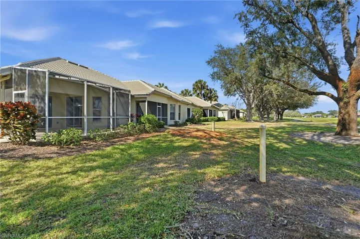 View of grassy yard featuring a sunroom and glass enclosure