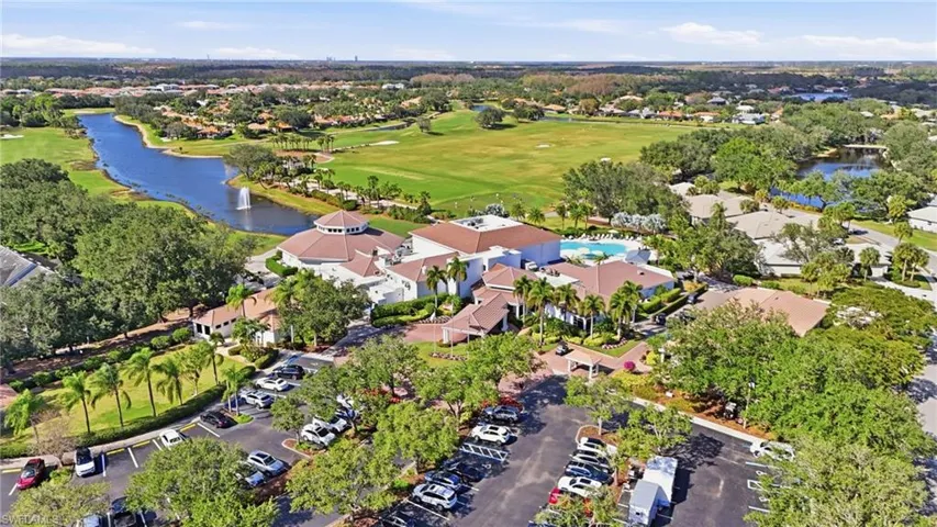 Aerial view of property and surrounding area featuring a golf course and a large body of water
