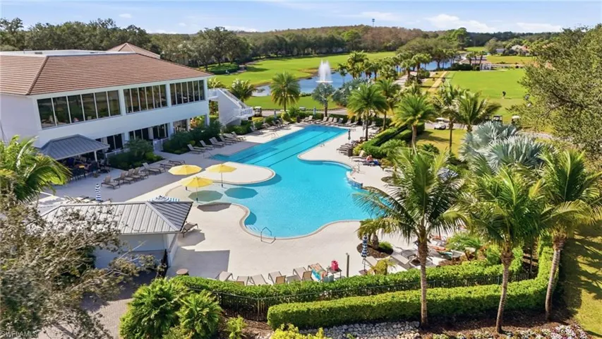 Community pool with a patio, view of scattered trees, and a water view