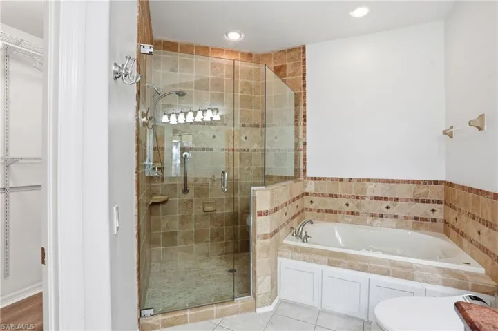 Bathroom with a bath, a walk in closet, a stall shower, recessed lighting, and tile patterned floors