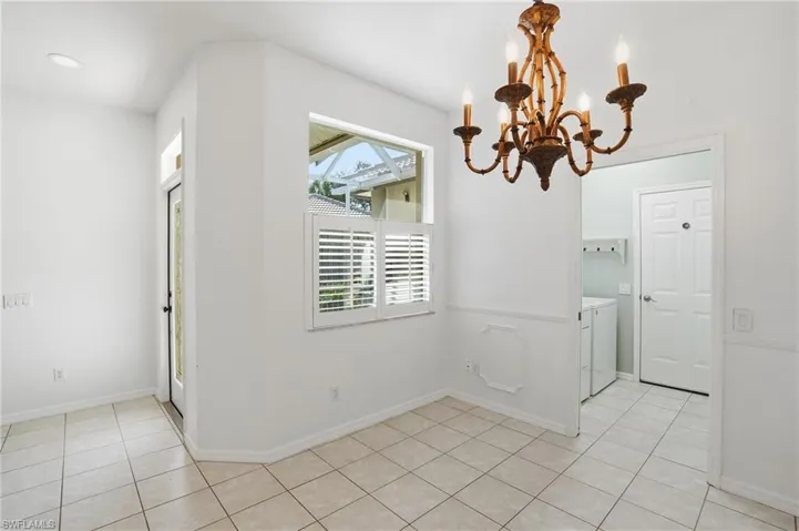 Unfurnished dining area with a chandelier, light tile patterned floors, and washer and clothes dryer
