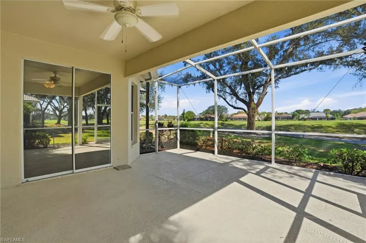 Unfurnished sunroom featuring a ceiling fan, a patio, and a residential view