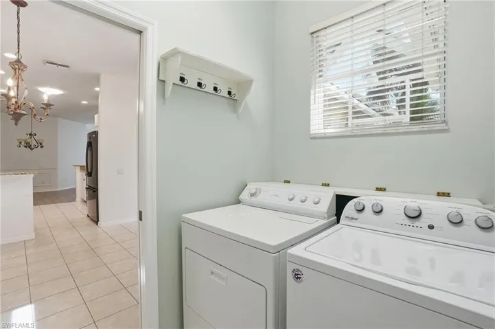Laundry area featuring light tile patterned flooring, independent washer and dryer, and a chandelier