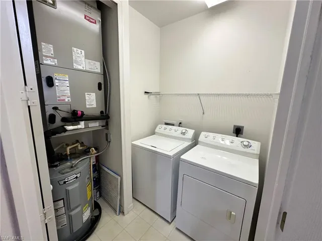 Washroom with light tile patterned flooring, washer and clothes dryer, furnace and water heater - all new systems